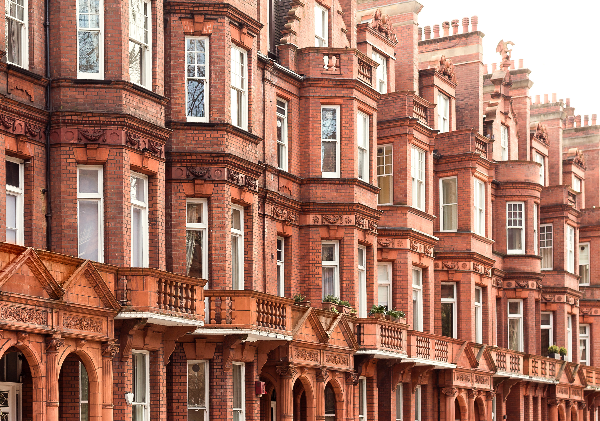 Houses – row of traditional, smart terraced buildings in city street. Exterior town houses. Typical architecture of urban residential street areas on sunny summer day. Real estate market opportunity.